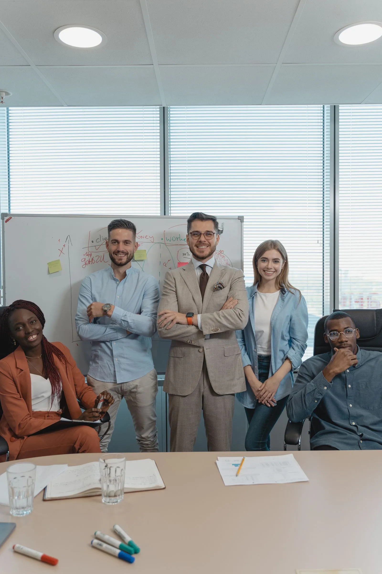Smiling, diverse team of coworkers standing together in a bright modern office